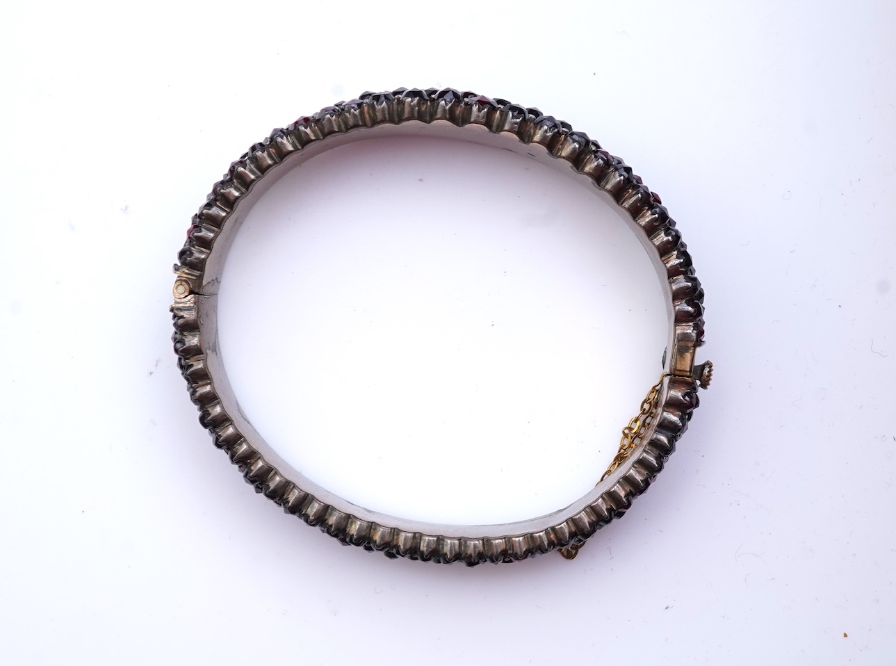 A suite of garnet and paste jewellery, comprising: a brooch, 5cm diameter; a bangle, inner circumference 16cm; two rings, sizes I and M; a pair of earrings, and a single earring, each set with rose-cut garnets; and a pai